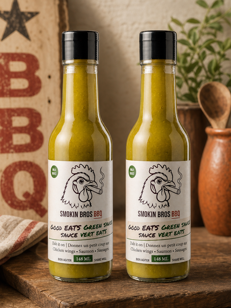 Two bottles of Smokin Bros BBQ Goos EATS Green Sauce standing on a rustic wooden surface, with a vintage-style BBQ sign, cloth, and terracotta pot in the background.
