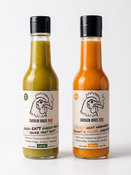 Two glass bottles of Smokin Bros BBQ hot sauce on a light gray background. The left bottle contains green sauce and is labeled 'Good Eats Green Sauce', and the right bottle contains orange sauce and is labeled 'Sweet Heat Habanero'.