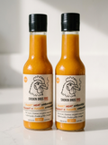 Two bottles of Smokin Bros BBQ Sweet Heat Habanero sauce with orange sauce, cream labels, and black caps, standing on a white surface against a white background.