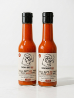 Two bottles of Smokin Bros BBQ Good Eats Red Sauce standing side by side on a white surface against a white background.